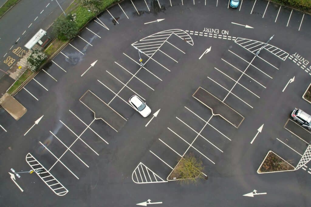 pexels-altaf-shah-3143825-16141619 Aerial view of an almost empty parking lot with a few cars and clear directional markings. | Sky Rye Design Aerial view of an almost empty parking lot with a few cars and clear directional markings.