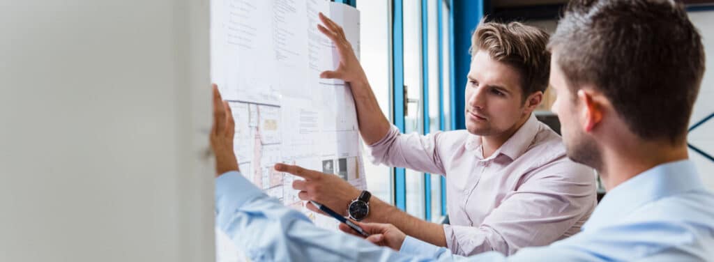 planning_discussion_1920x705hero Two men discussing architectural blueprints in a modern office setting. | Sky Rye Design Two men discussing architectural blueprints in a modern office setting.