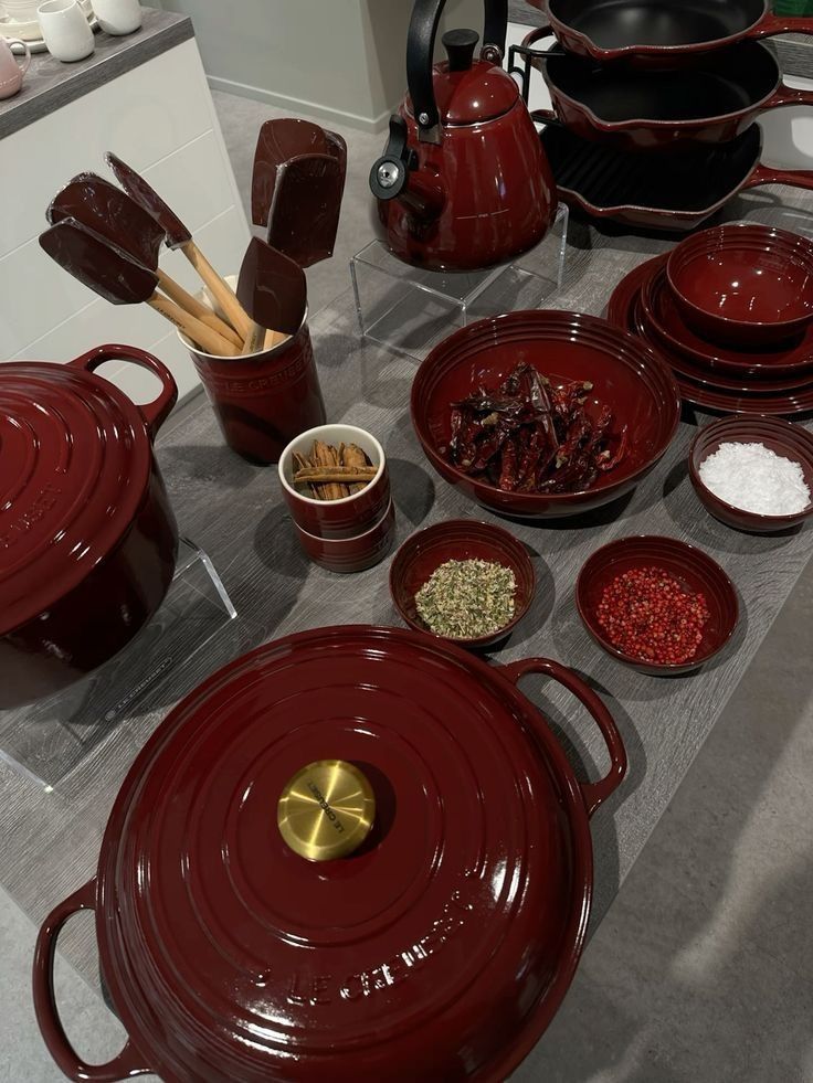 redwine kitchen vibe Red cookware set with pots, pans, and herbs on a kitchen counter; modern culinary tools and spices. | Sky Rye Design Red cookware set with pots, pans, and herbs on a kitchen counter; modern culinary tools and spices.