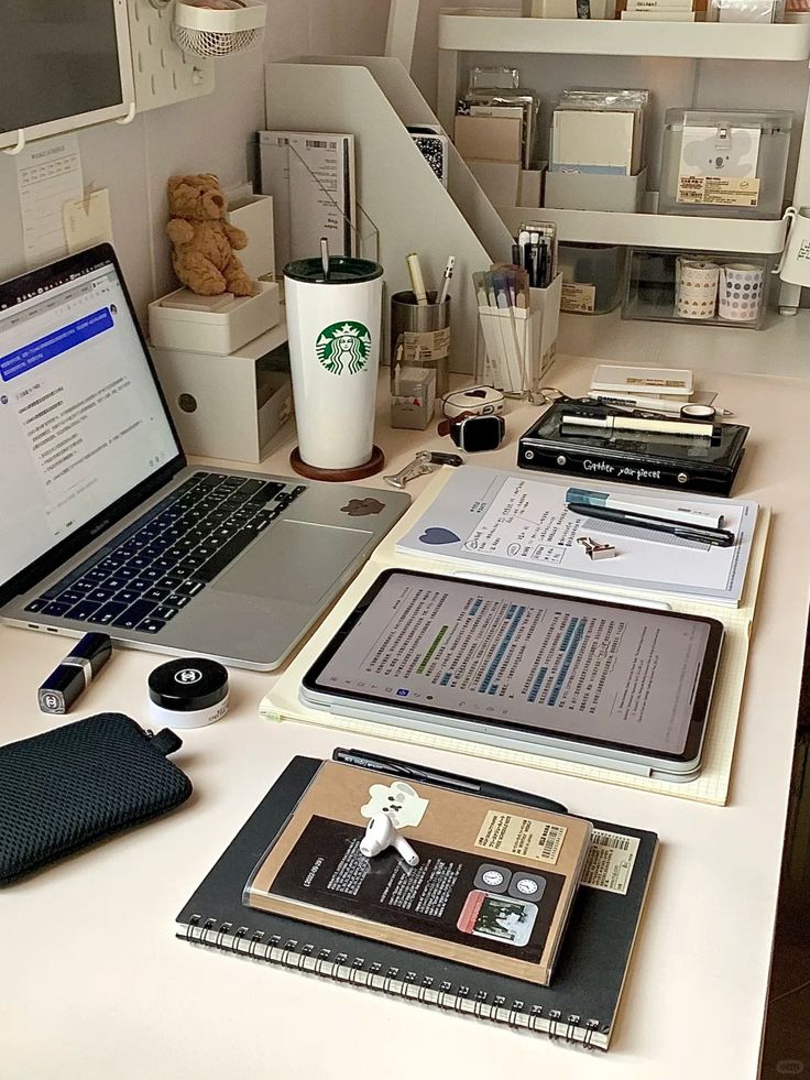 rtgrtgmrl Organized desk setup with laptop, tablet, notebooks, and stationary, featuring a Starbucks cup and shelves in the background. | Sky Rye Design Organized desk setup with laptop, tablet, notebooks, and stationary, featuring a Starbucks cup and shelves in the background.