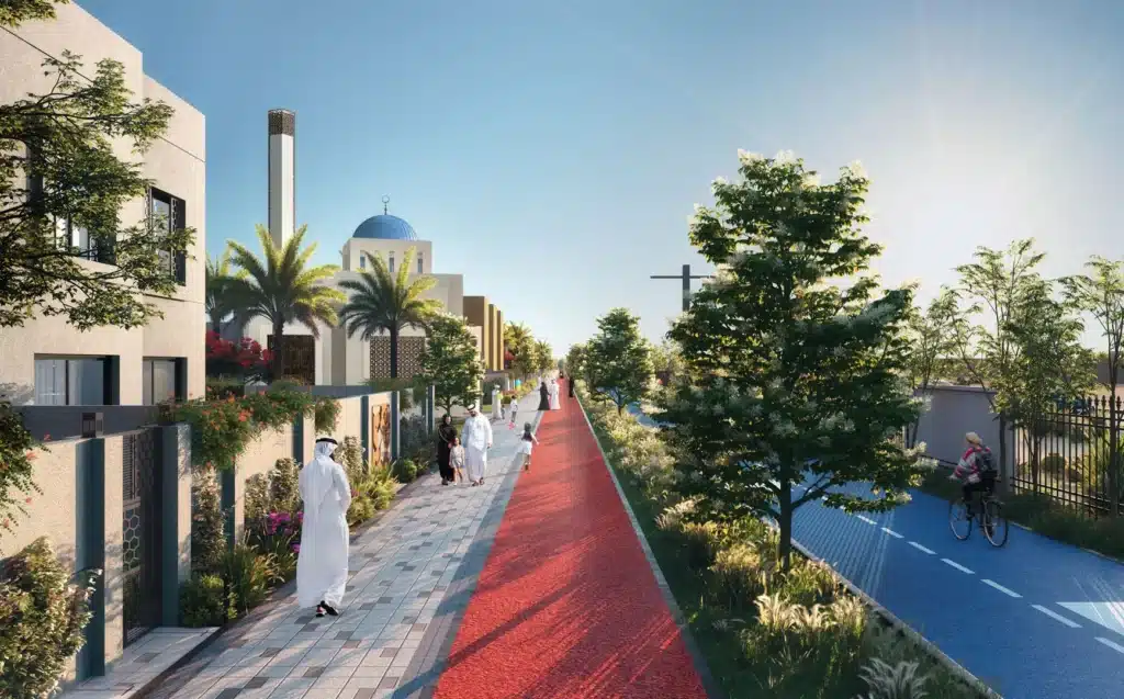 Street view with people walking and biking along a tree-lined path under a clear blue sky.