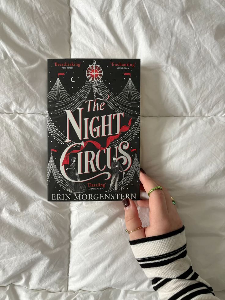 the night circus book books aesthetic rings darkvibes Hand holding The Night Circus by Erin Morgenstern on a white blanket, showcasing its elegant black cover design. | Sky Rye Design Hand holding The Night Circus by Erin Morgenstern on a white blanket, showcasing its elegant black cover design.
