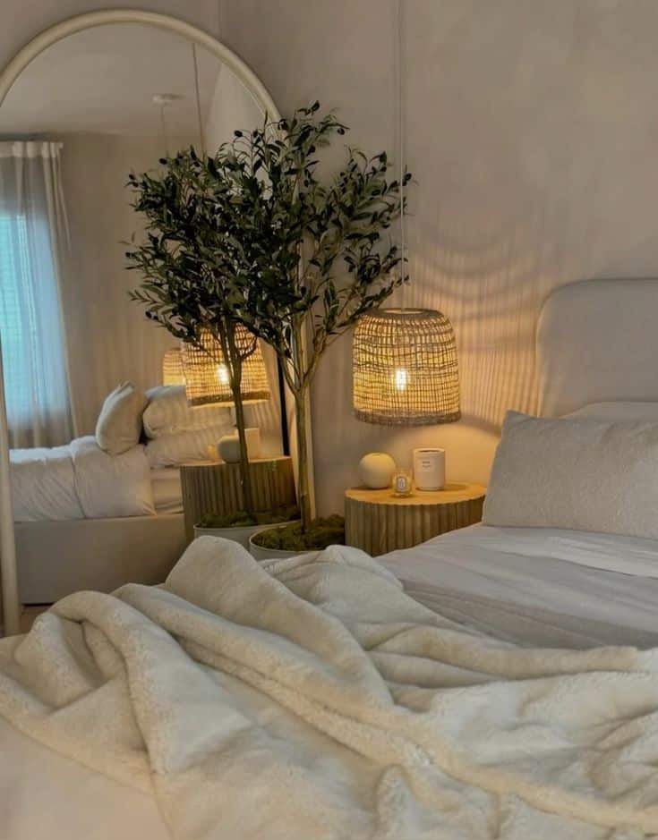 throughthegreydoor Cozy bedroom with a soft bed, fluffy blankets, warm lighting, and a decorative potted plant beside a wooden nightstand. | Sky Rye Design Cozy bedroom with a soft bed, fluffy blankets, warm lighting, and a decorative potted plant beside a wooden nightstand.