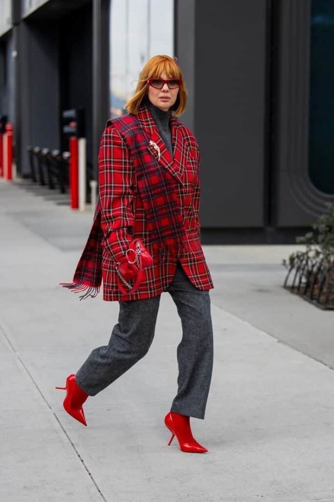 _ Stylish woman in red plaid coat and boots walking confidently on city street. | Sky Rye Design Stylish woman in red plaid coat and boots walking confidently on city street.