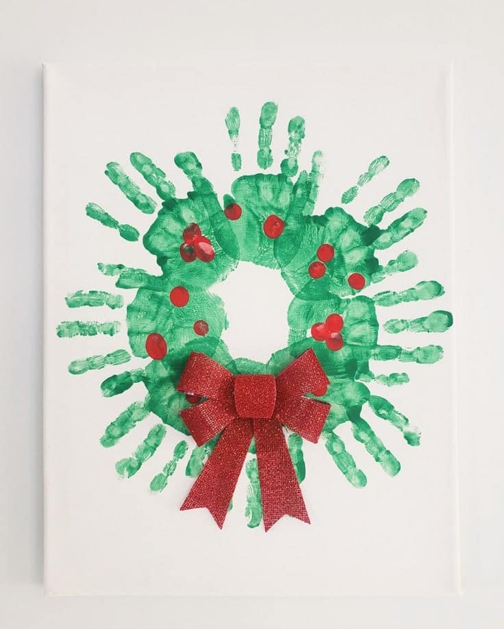 Handprint Christmas wreath with red bow and berries, DIY holiday decor craft for kids.