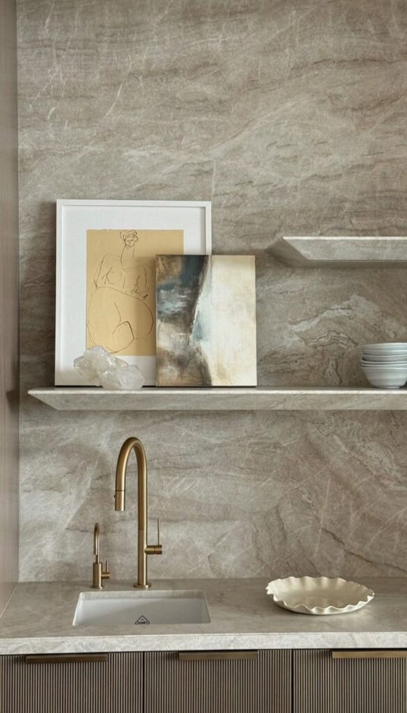 _ Minimalist kitchen with beige marble backsplash, gold faucet, and art decor on shelves. Modern and elegant design. | Sky Rye Design Minimalist kitchen with beige marble backsplash, gold faucet, and art decor on shelves. Modern and elegant design.