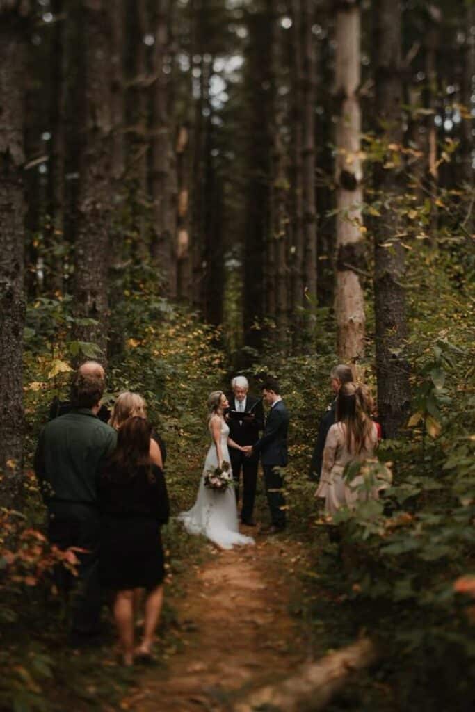Bride and groom exchanging vows in a serene forest setting during an intimate outdoor wedding ceremony.
