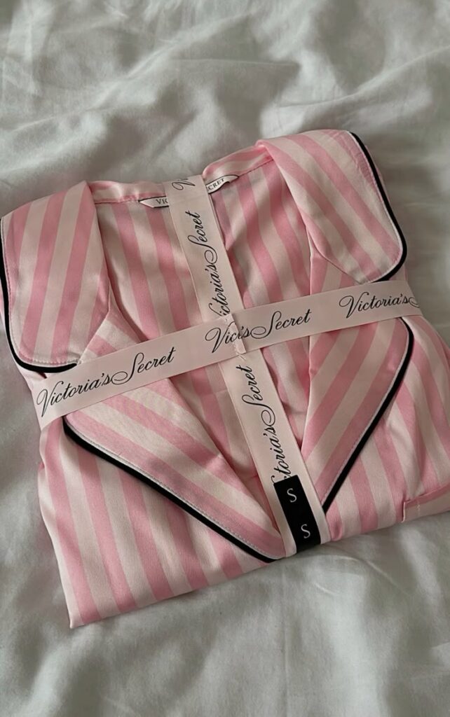 Pink striped Victoria's Secret pajamas neatly folded with branded ribbon on white background.