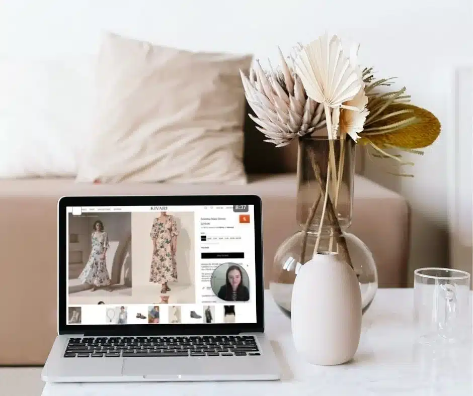 weekly-style-videos Laptop displaying online shopping for floral dresses, placed on a table beside a modern vase with dried flowers. | Sky Rye Design Laptop displaying online shopping for floral dresses, placed on a table beside a modern vase with dried flowers.