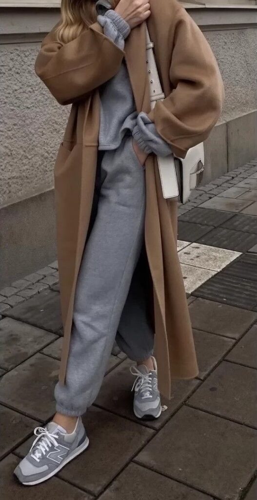 Fashionable streetwear: grey tracksuit, brown coat, sneakers, and white crossbody bag. Urban casual style.