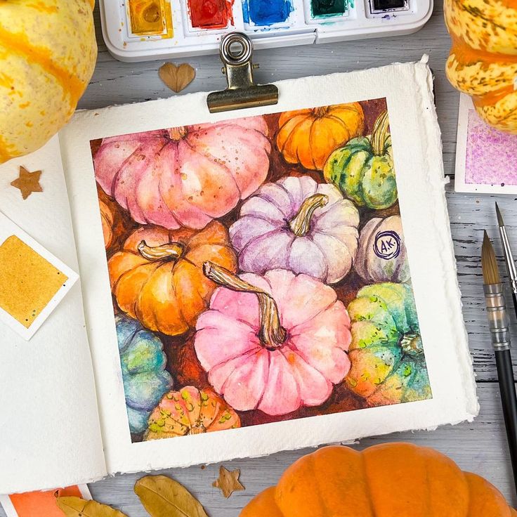Watercolor pumpkin painting with vibrant colors, surrounded by art supplies and autumn decor.