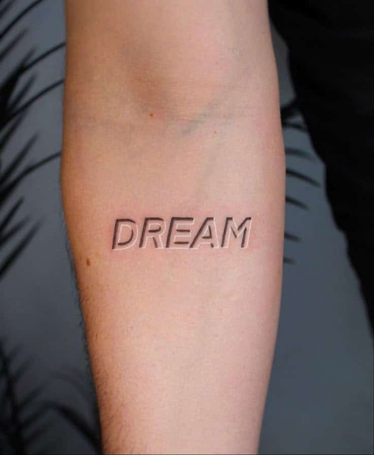 Arm tattoo with the word DREAM in raised lettering, symbolizing inspiration and aspirations.