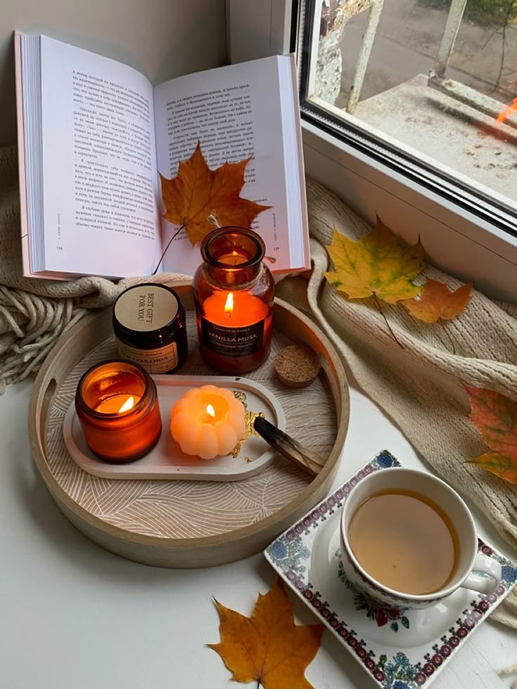 эстетика осень Cozy autumn setup with lit candles, open book, and tea by the window, surrounded by fall leaves and warm decor. | Sky Rye Design Cozy autumn setup with lit candles, open book, and tea by the window, surrounded by fall leaves and warm decor.
