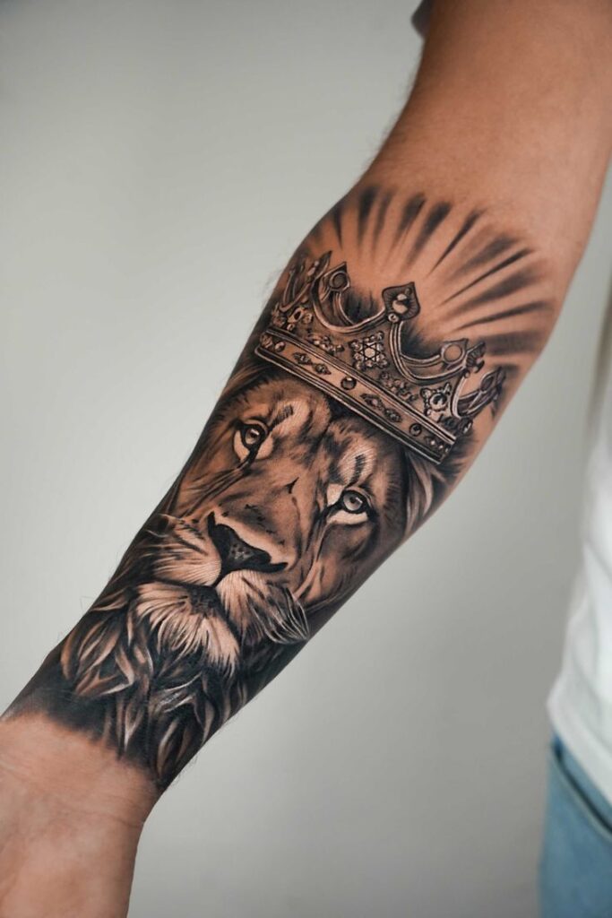 קעקוע ריאליסטי בגון בוי קעקועים- תל אביב Lion with crown tattoo on forearm, showcasing intricate details and powerful symbolism. | Sky Rye Design Lion with crown tattoo on forearm, showcasing intricate details and powerful symbolism.