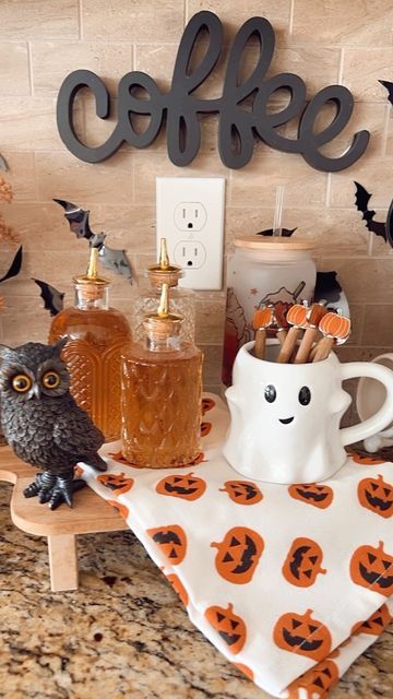 Halloween-themed coffee bar with owl figurine, ghost mug, pumpkin napkin, and bat decorations.