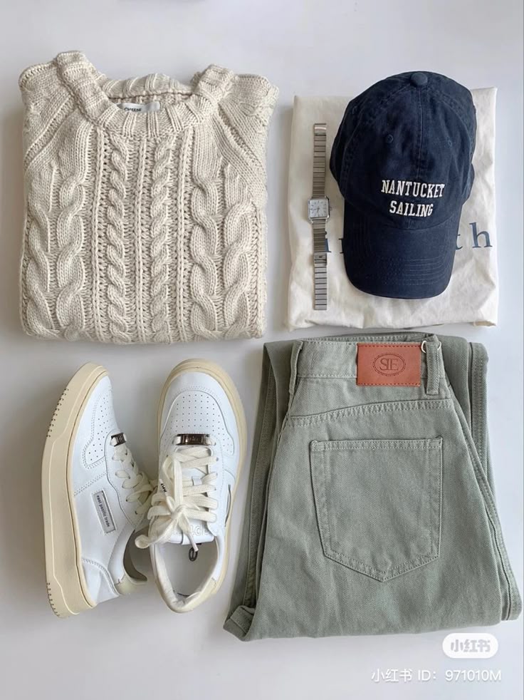 Flat lay of cozy fall outfit with cable-knit sweater, green pants, white sneakers, navy cap, and a watch.