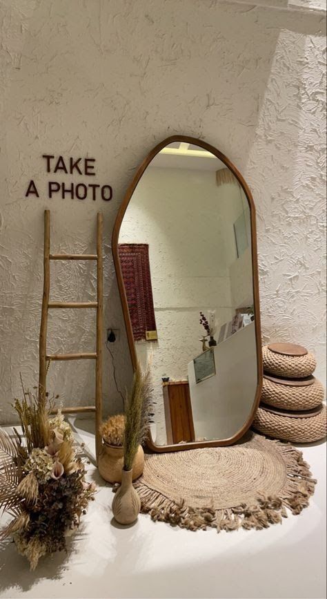 Stylish room decor with rustic ladder, large mirror, dried flowers, and accents on textured wall reading Take a Photo.