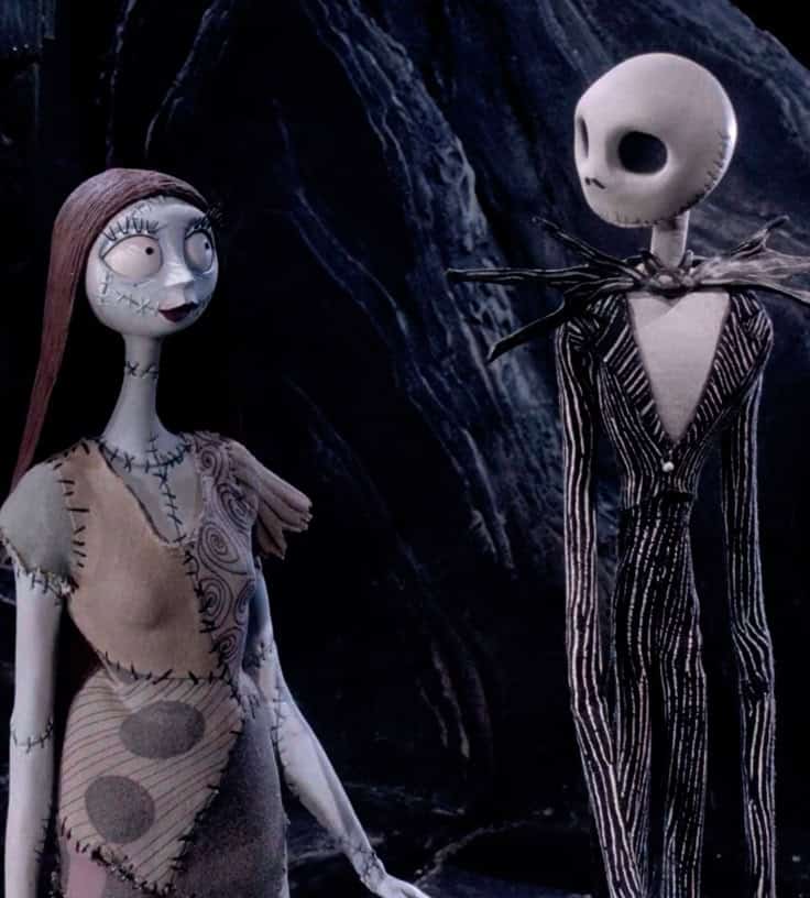Two animated characters from a stop-motion film stand together in a dark, moody setting, featuring stitched costumes.