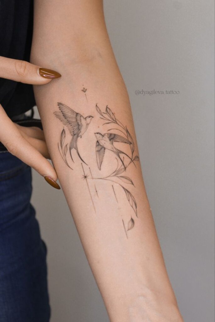 Ласточки тату 🤍 Minimalist tattoo of birds and leaves on forearm, fine line art design, displayed on skin. | Sky Rye Design Minimalist tattoo of birds and leaves on forearm, fine line art design, displayed on skin.