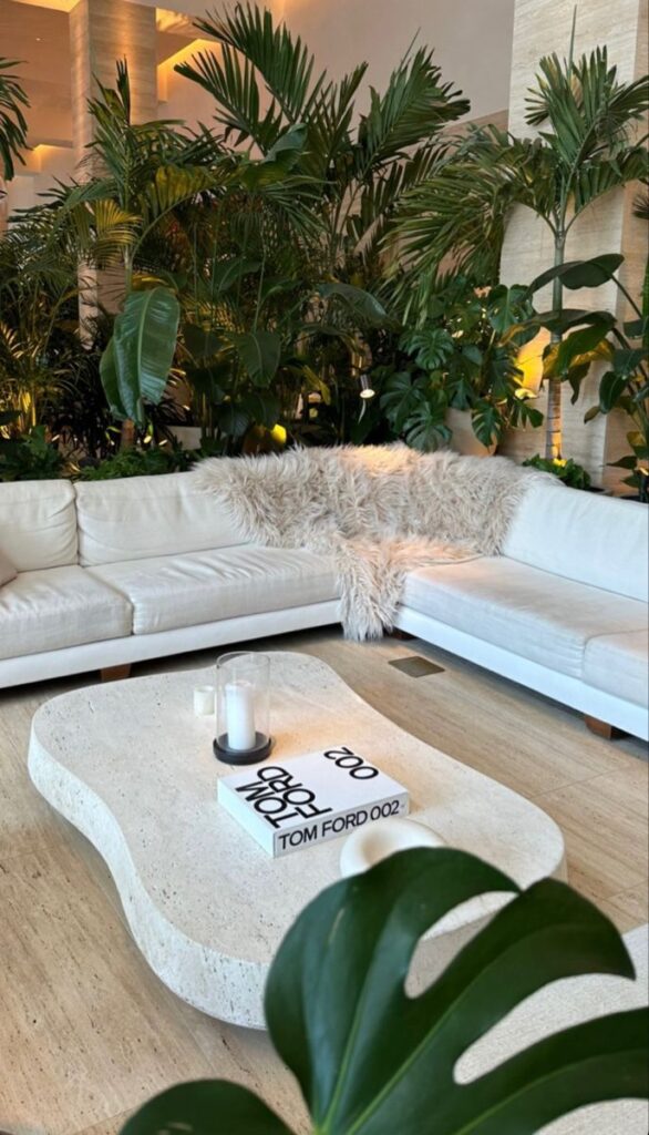 𝓐_𝓡 Modern living room with white sofa, lush plants, and stone coffee table with books and candles. Cozy and stylish decor. | Sky Rye Design Modern living room with white sofa, lush plants, and stone coffee table with books and candles. Cozy and stylish decor.