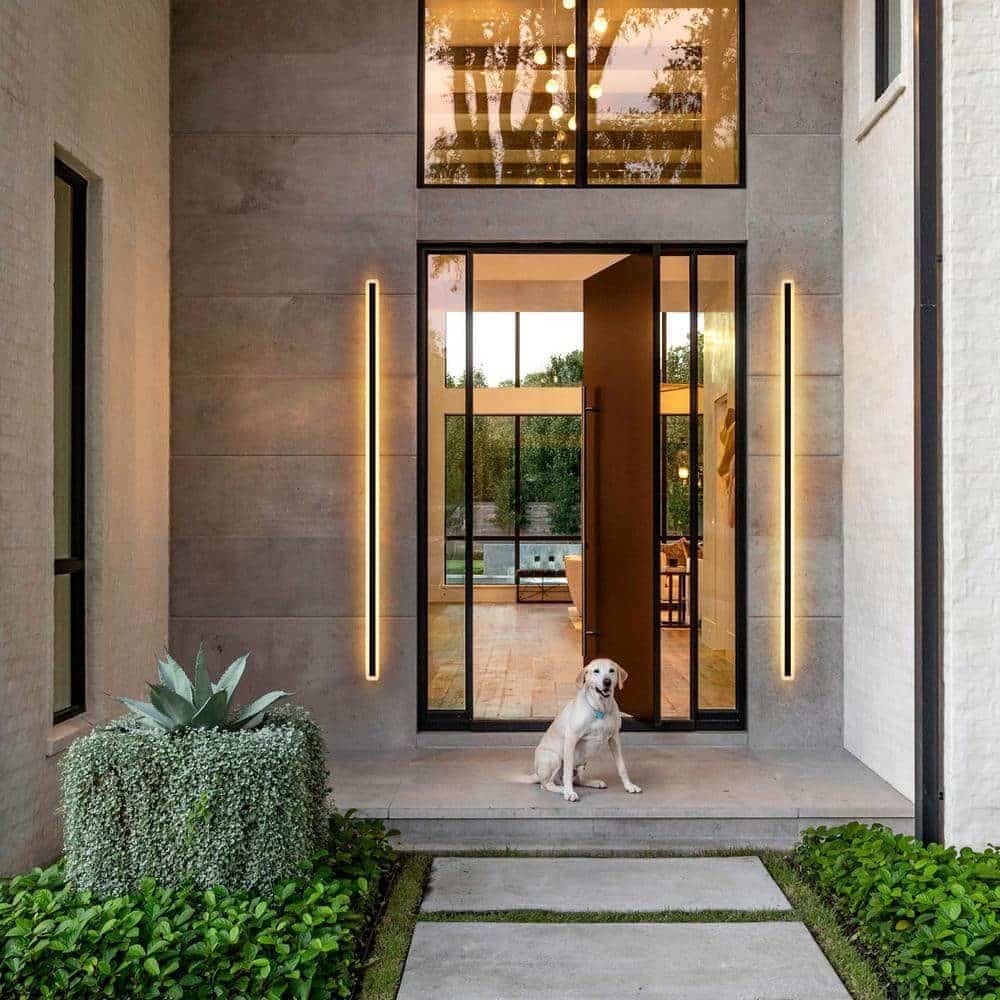 07beef4d85d7ff50094767e0b6a57db4 Modern home entrance with large glass door and warm lighting, featuring a white dog sitting outside. | Sky Rye Design Modern home entrance with large glass door and warm lighting, featuring a white dog sitting outside.