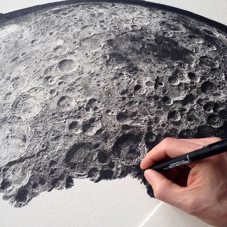 Artist sketching detailed moon surface with ink pen, highlighting craters and textures in black and white.