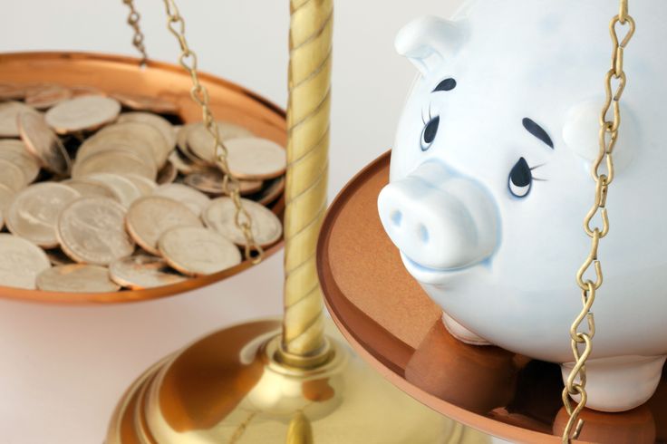 A Blue Piggy Bank and Gold Coins on a Brass Copper Colored Balance Scale Piggy bank balanced with coins on scales, symbolizing savings and financial balance. | Sky Rye Design Piggy bank balanced with coins on scales, symbolizing savings and financial balance.