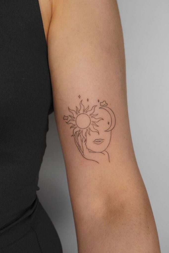 100c4acd-e891-47e8-bbac-1fc1e4a56e6c Minimalistic tattoo of a face with sun and moon on upper arm, blending celestial elements with human features, set against a plain backdrop. | Sky Rye Design Minimalistic tattoo of a face with sun and moon on upper arm, blending celestial elements with human features, set against a plain backdrop.