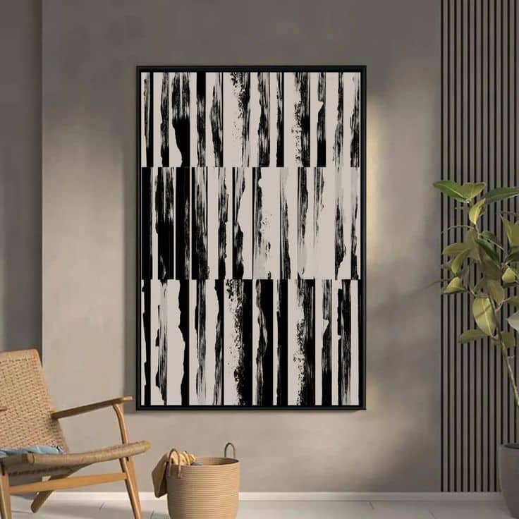 Abstract black and white vertical canvas art in modern living room with chair, plant, and soft lighting.