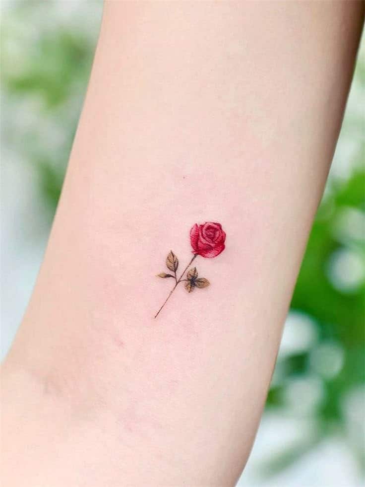 Delicate small rose tattoo on arm, showcasing intricate details and vibrant red petals, symbolizing beauty and elegance.