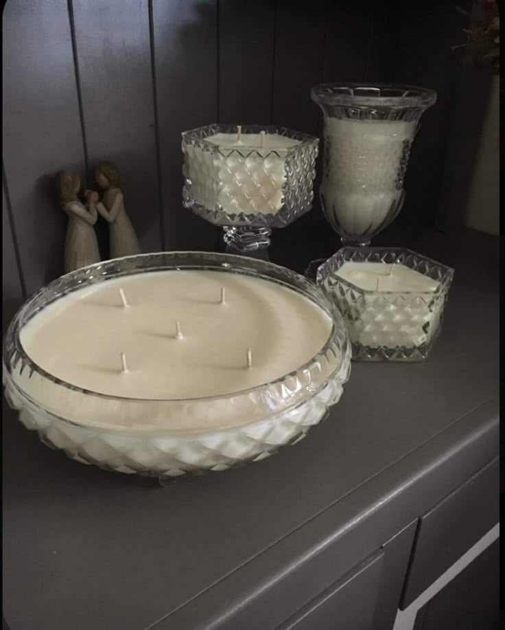 Elegant crystal bowl candles on a shelf next to decorative figurines, adding a warm, cozy touch to the dark interior setting.