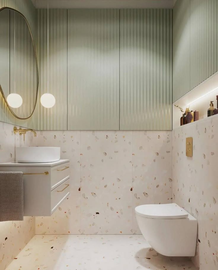 Modern bathroom with terrazzo tiles, wall-mounted toilet, stylish vanity, and oval mirror.