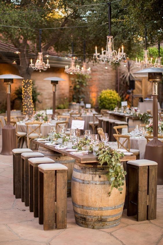 _ 13 Rustic outdoor wedding reception setup with barrel tables, wooden chairs, chandeliers, and greenery, creating a charming, elegant ambiance. | Sky Rye Design Rustic outdoor wedding reception setup with barrel tables, wooden chairs, chandeliers, and greenery, creating a charming, elegant ambiance.