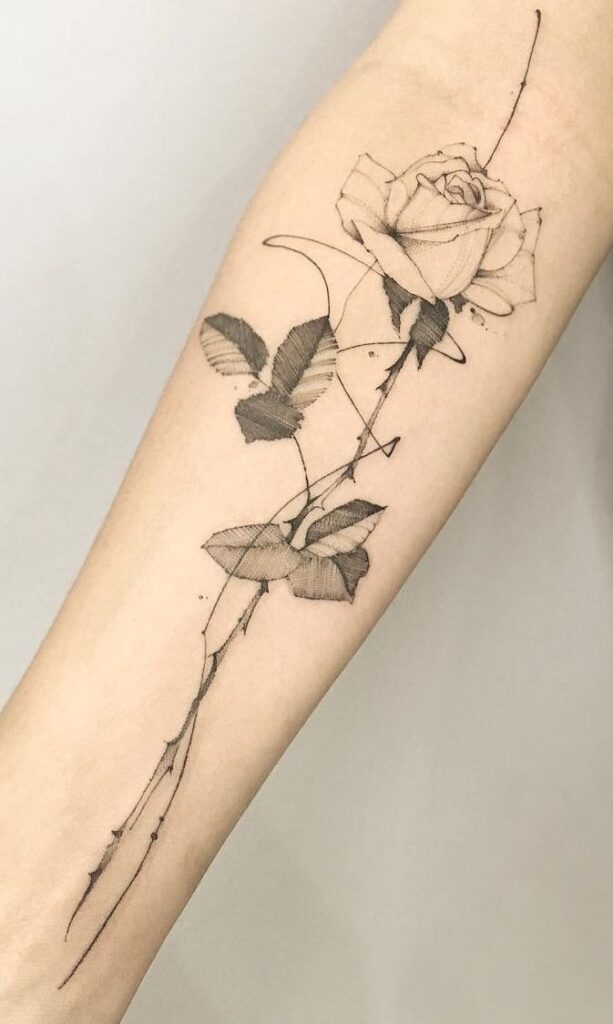 Detailed black line rose tattoo on forearm, with shading and intricate leaves, showcasing delicate floral artistry.