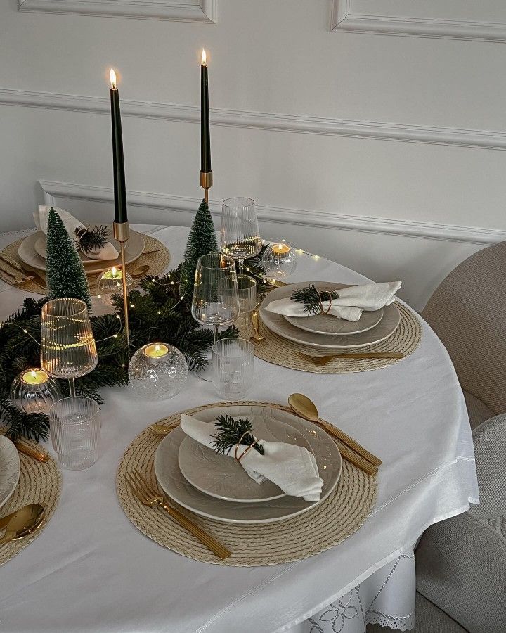 Elegant holiday dining table with green candles, festive decor, and twinkling lights, set for a cozy, intimate celebration.