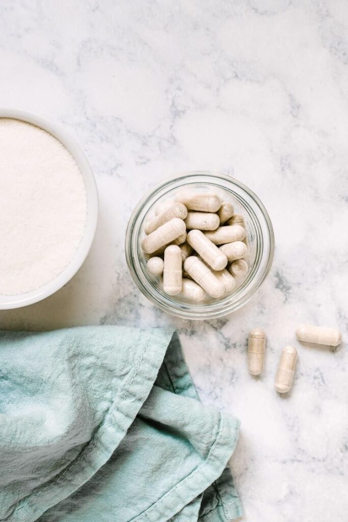 _ 13 Jar of white capsules with a bowl of powder on marble surface, next to a green cloth. | Sky Rye Design Jar of white capsules with a bowl of powder on marble surface, next to a green cloth.