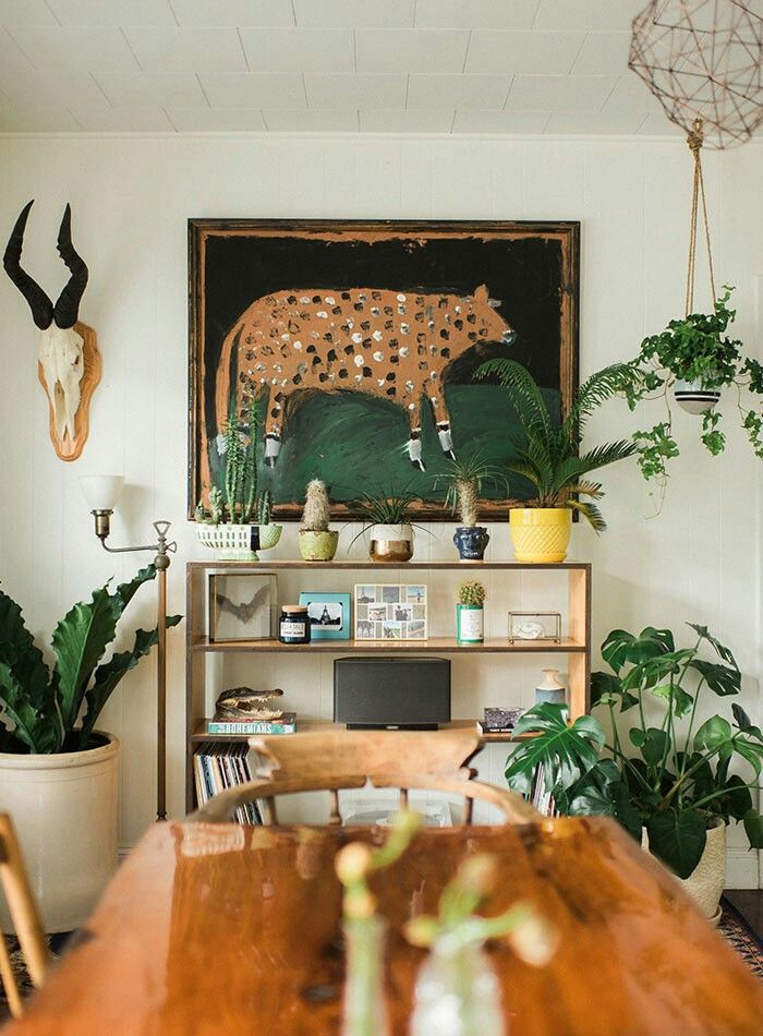 _ 14 Eclectic living room with leopard painting, plants, a wooden shelf, and antelope skull wall art. Bohemian interior decor. | Sky Rye Design Eclectic living room with leopard painting, plants, a wooden shelf, and antelope skull wall art. Bohemian interior decor.