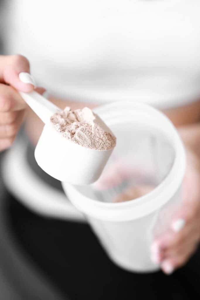 _ 14 A scoop of protein powder being poured into a shaker bottle for a fitness drink. | Sky Rye Design A scoop of protein powder being poured into a shaker bottle for a fitness drink.
