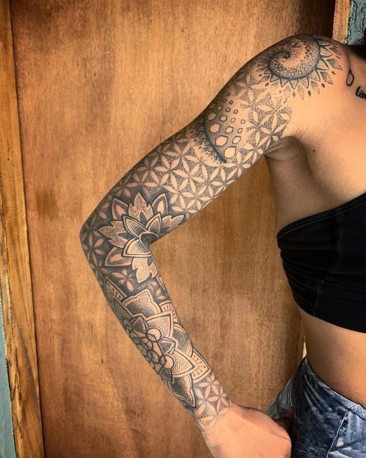 Intricate geometric sleeve tattoo design on a woman's arm, featuring floral and mandala patterns.