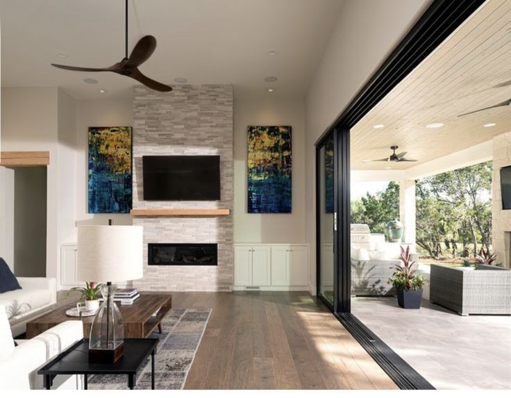 _ 16 Modern living room with fireplace, wall art, and open patio door to outdoor seating area. | Sky Rye Design Modern living room with fireplace, wall art, and open patio door to outdoor seating area.