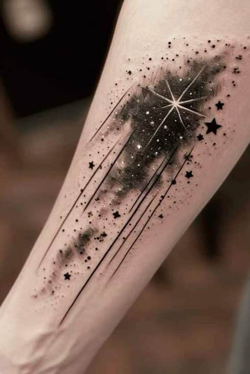 Arm tattoo with a cosmic galaxy design featuring stars and a shining comet trail.