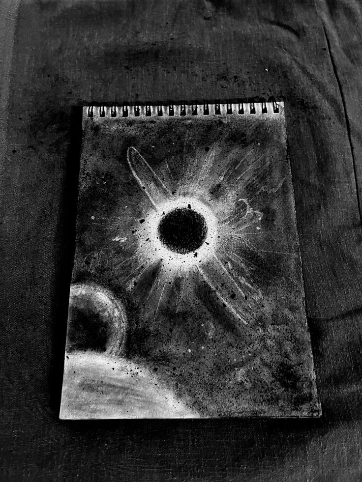 Black and white cosmic sketch of an eclipse and planets on paper, highlighting artistic space exploration and creativity.