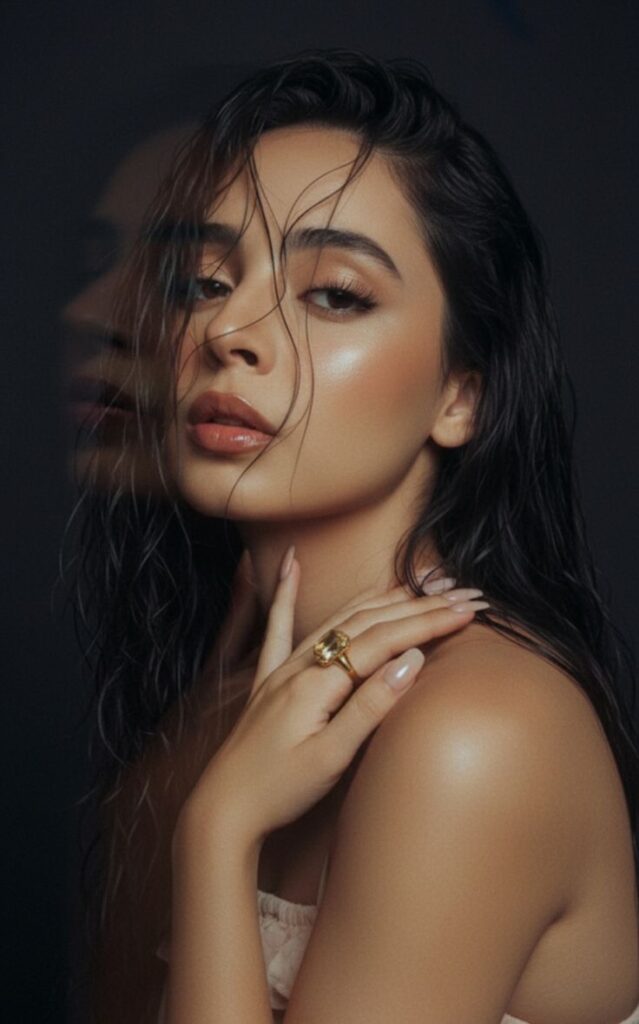 Woman with wet hair and glowing skin, wearing a gold ring, strikes a stylish pose against a dark background. Fashion and beauty concept.