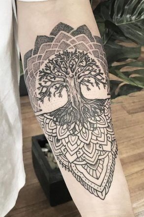 Detailed tree of life tattoo with geometric patterns on forearm, black ink, intricate design.