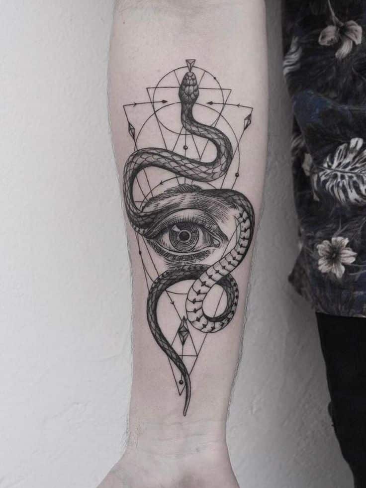 _ 19 Tattoo of a snake wrapped around an eye on a geometric background, inked on a forearm. | Sky Rye Design Tattoo of a snake wrapped around an eye on a geometric background, inked on a forearm.
