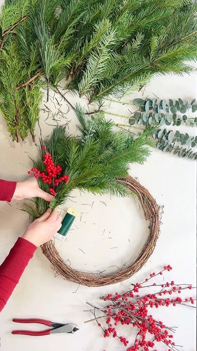 192a68e5c383310421abb2806f1f8aa5 Creating a festive wreath with pine branches, red berries, and eucalyptus on a crafting table. Holiday decor DIY project in progress. | Sky Rye Design Creating a festive wreath with pine branches, red berries, and eucalyptus on a crafting table. Holiday decor DIY project in progress.
