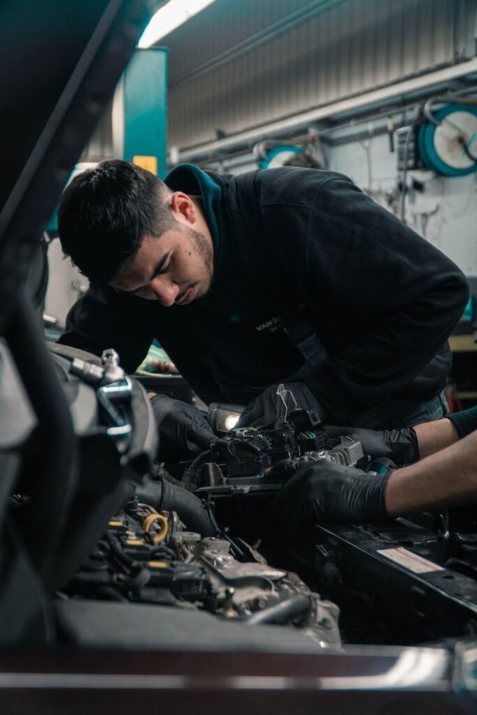 _ 2 Mechanic focused on car engine repair in an auto shop, showcasing automotive expertise and precision. | Sky Rye Design Mechanic focused on car engine repair in an auto shop, showcasing automotive expertise and precision.