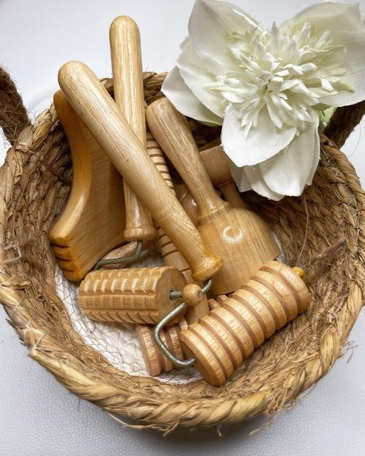 Woven basket with wooden massage tools and a white flower, perfect for natural relaxation and self-care routines.
