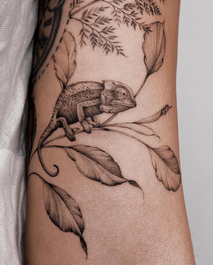 _ 2 Detailed black and gray tattoo of a chameleon on a branch with leaves, wrapped around an arm. | Sky Rye Design Detailed black and gray tattoo of a chameleon on a branch with leaves, wrapped around an arm.
