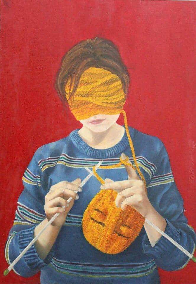 Person knitting with eyes covered by orange yarn on a red background, wearing a blue striped sweater, creativity concept.